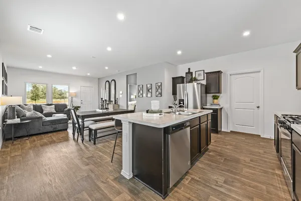 a large kitchen with stainless steel appliances a large counter top a stove and a refrigerator