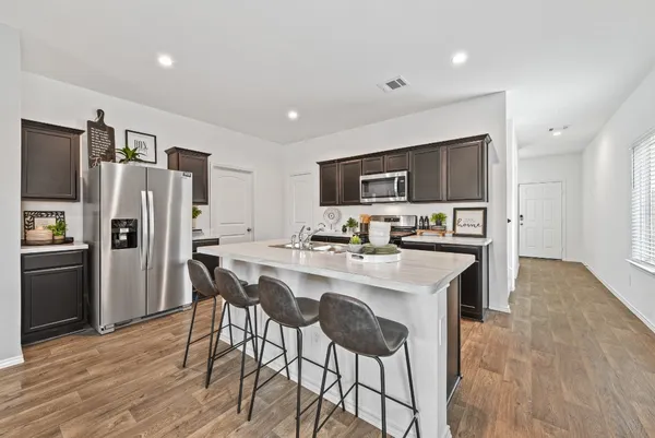 a kitchen with stainless steel appliances a refrigerator a stove a sink a dining table and chairs