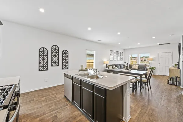 a room with stainless steel appliances granite countertop a dining table chairs and wooden floor