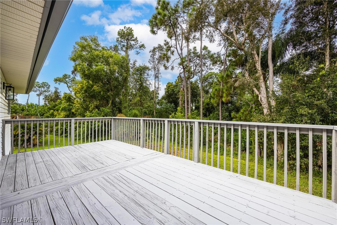 18804 Matanzas Road Fort Myers, FL 33967 - Photo 5 of 19 a balcony with wooden floor and trees in the back