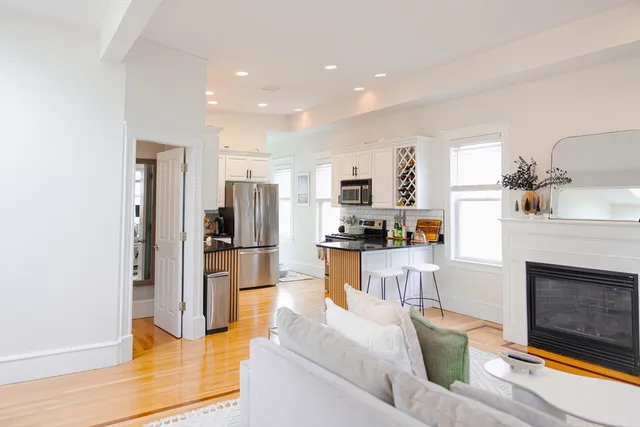 a living room with stainless steel appliances kitchen island granite countertop furniture and a fireplace