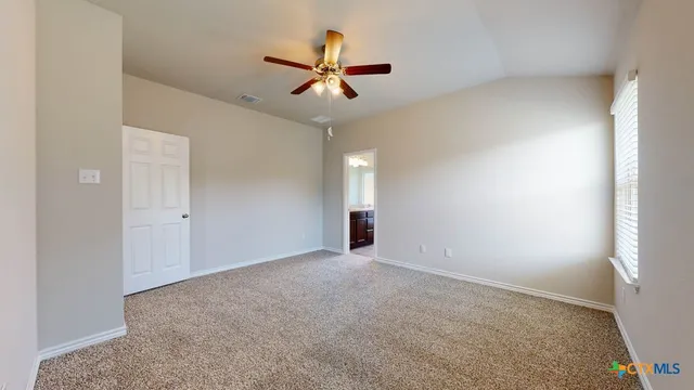 an empty room with ceiling fan and window