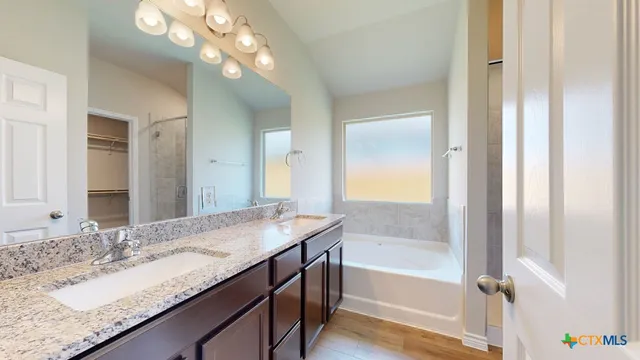a bathroom with a granite countertop sink a bathtub and a mirror