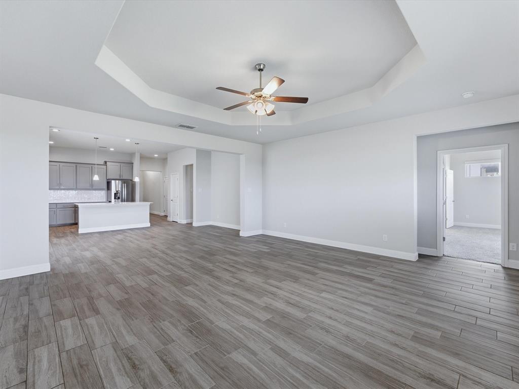 1121 Knightsbridge Road Argyle, TX 76226 - Photo 22 of 39 Spacious living area featuring wood-look tile flooring, a tray ceiling, and a ceiling fan