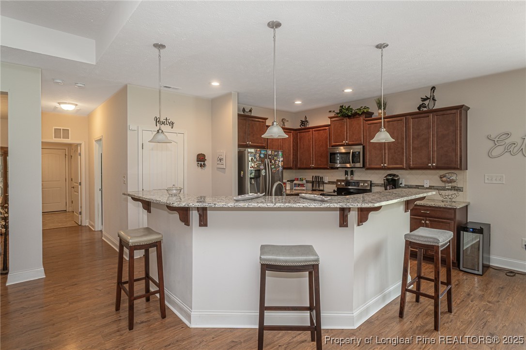 8220 Rivermist Lane Linden, NC 28356 - Photo 12 of 44 a kitchen with kitchen island granite countertop wooden floors and white cabinets