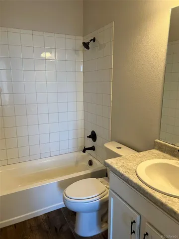 a bathroom with a granite countertop bathtub sink vanity mirror and toilet