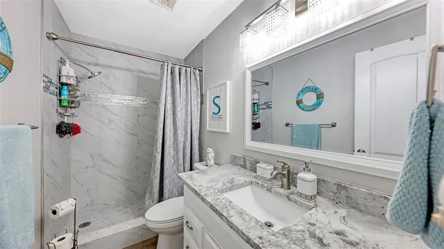 a bathroom with a granite countertop sink toilet a mirror and shower