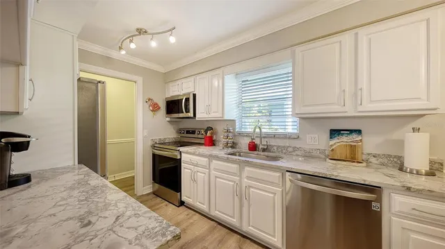 a kitchen with stainless steel appliances granite countertop a sink stove refrigerator and cabinets
