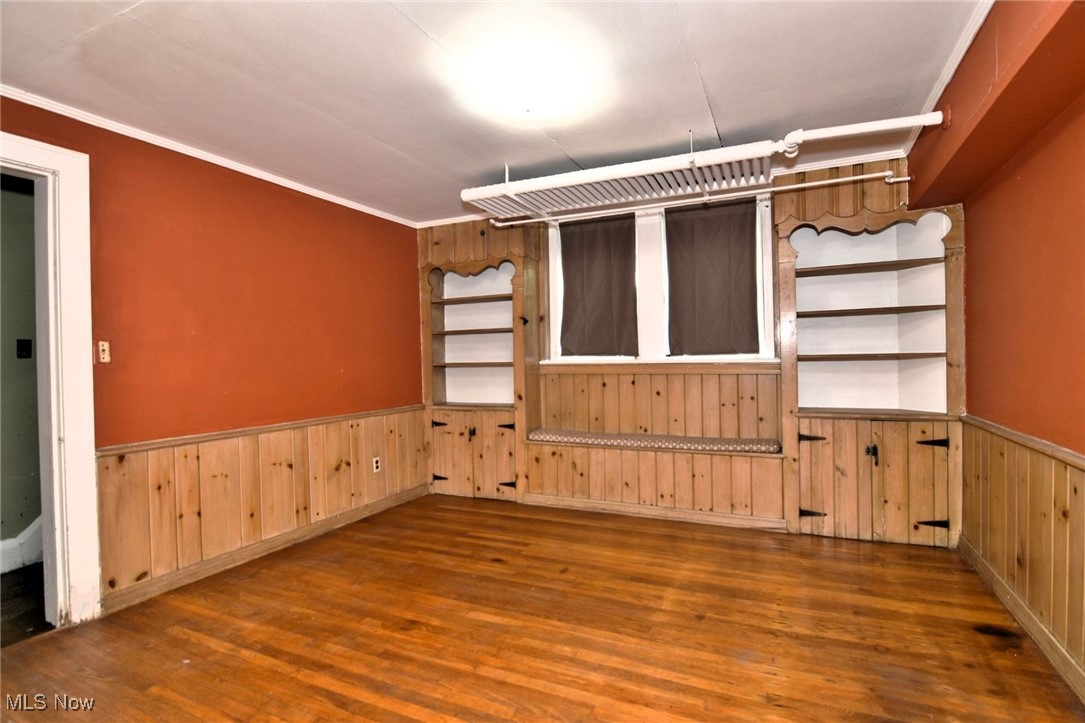 17930 Rosecliff Road Cleveland, OH 44119 - Photo 42 of 50 Empty room with wood finished floors, a wainscoted wall, wood walls, and crown molding