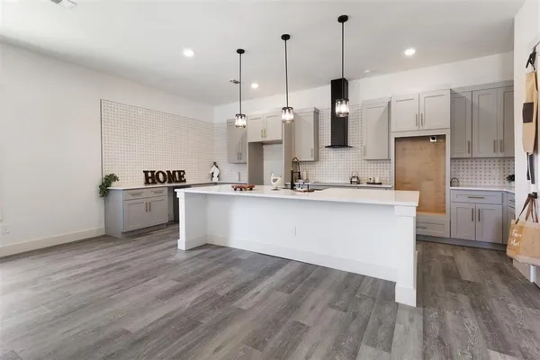 a large kitchen with stainless steel appliances kitchen island a large counter top a sink cabinets and a wooden floor