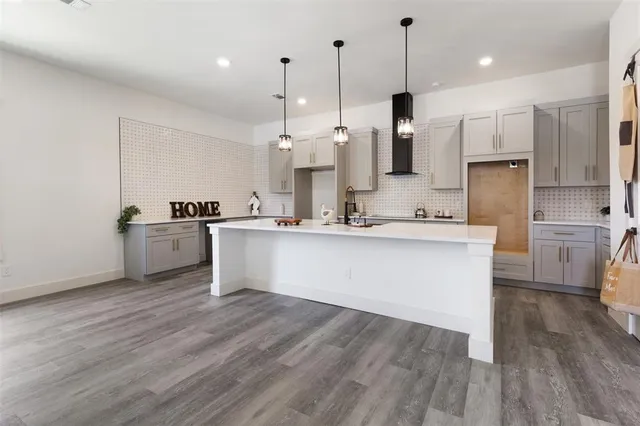 a large kitchen with stainless steel appliances kitchen island a large counter top a sink cabinets and a wooden floor