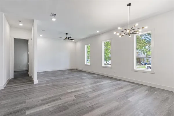 a view of an empty room with window and wooden floor