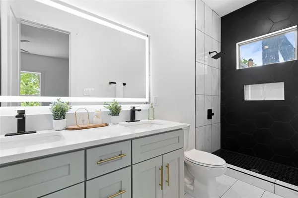 a bathroom with a granite countertop sink a toilet a mirror and shower