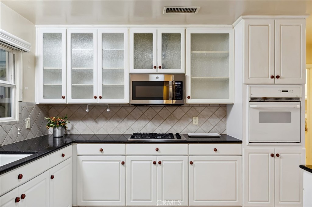 4254 Miramonte Place Riverside, CA 92501 - Photo 14 of 43 a kitchen with granite countertop white cabinets and stainless steel appliances