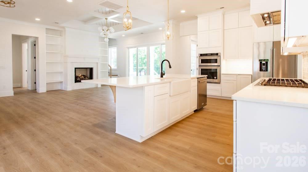 1 Antioch Church Road Weddington, NC 28104 - Photo 4 of 22 a large white kitchen with kitchen island a stove a sink a refrigerator and a fireplace