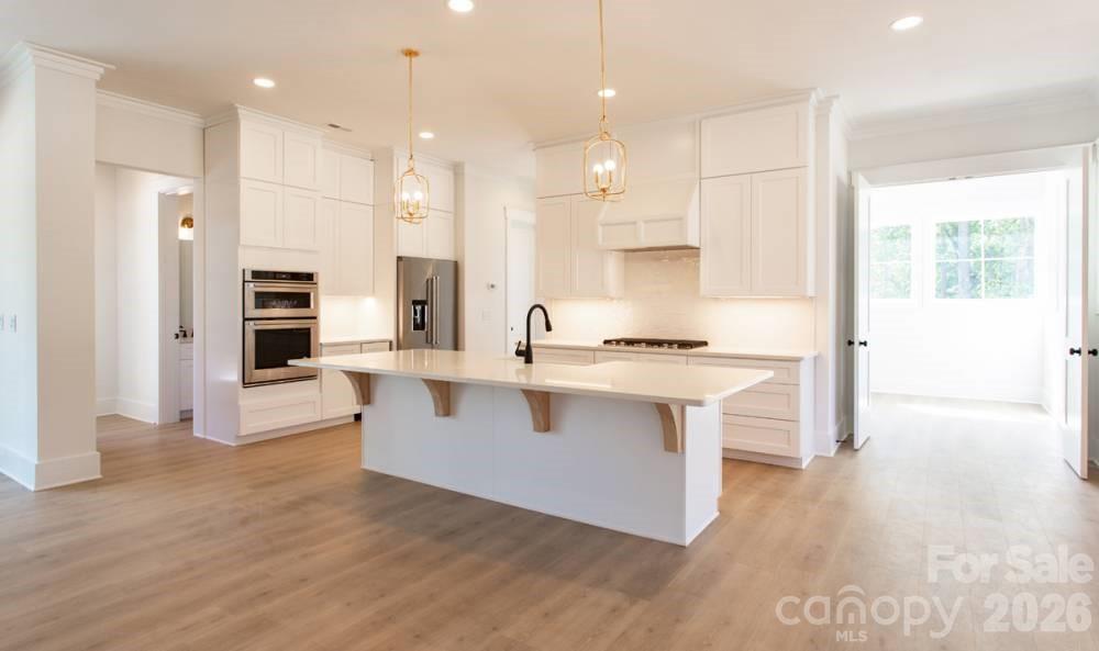 1 Antioch Church Road Weddington, NC 28104 - Photo 5 of 22 a large white kitchen with stainless steel appliances granite countertop a stove a sink a refrigerator and white cabinets with wooden floor next to windows