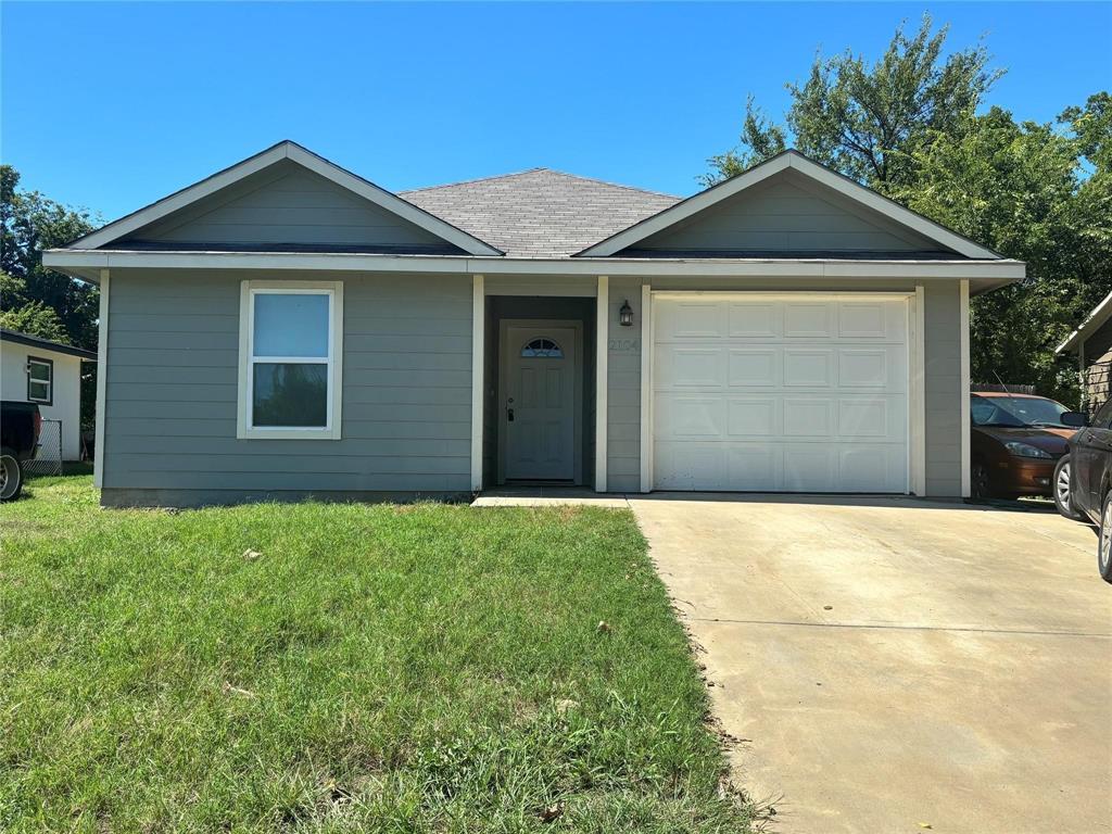 Ranch-style home with a front lawn, driveway, a garage, oil tank, and a shingled roof