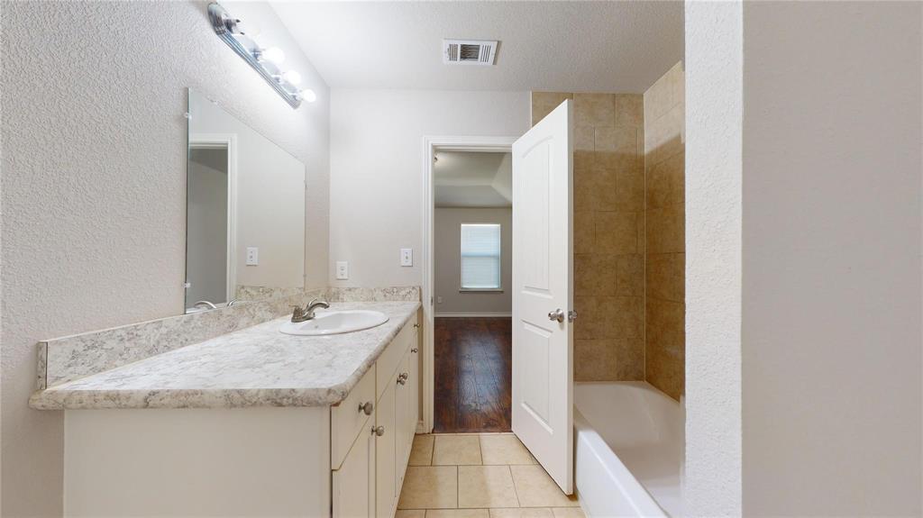 2104 Daniel Street Fort Worth, TX 76104 - Photo 12 of 12 Bathroom featuring vanity, a textured wall, and light tile patterned flooring