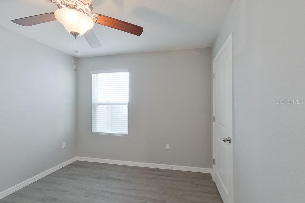 8656 Southwest 44th Court Ocala, FL 34476 - Photo 8 of 19 an empty room with wooden floor chandelier fan and windows