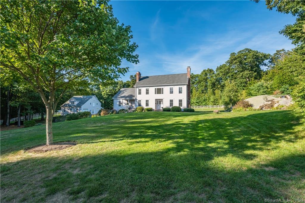 a view of a house next to a big yard and large trees