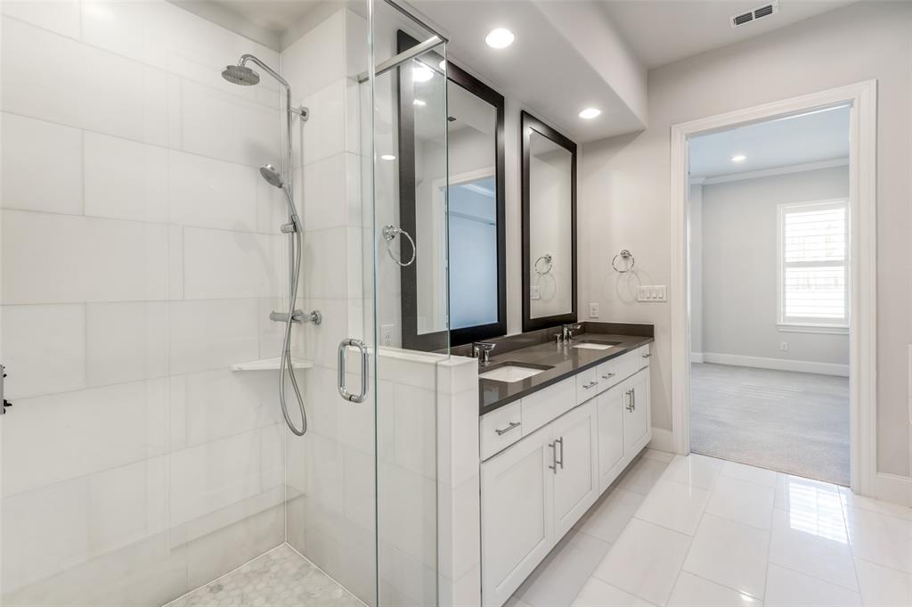 5421 Patterson Street Irving, TX 75039 - Photo 17 of 32 Contemporary bathroom featuring a glass-enclosed shower with a bench, a dual vanity with a dark countertop, white cabinetry, and large format floor tiling