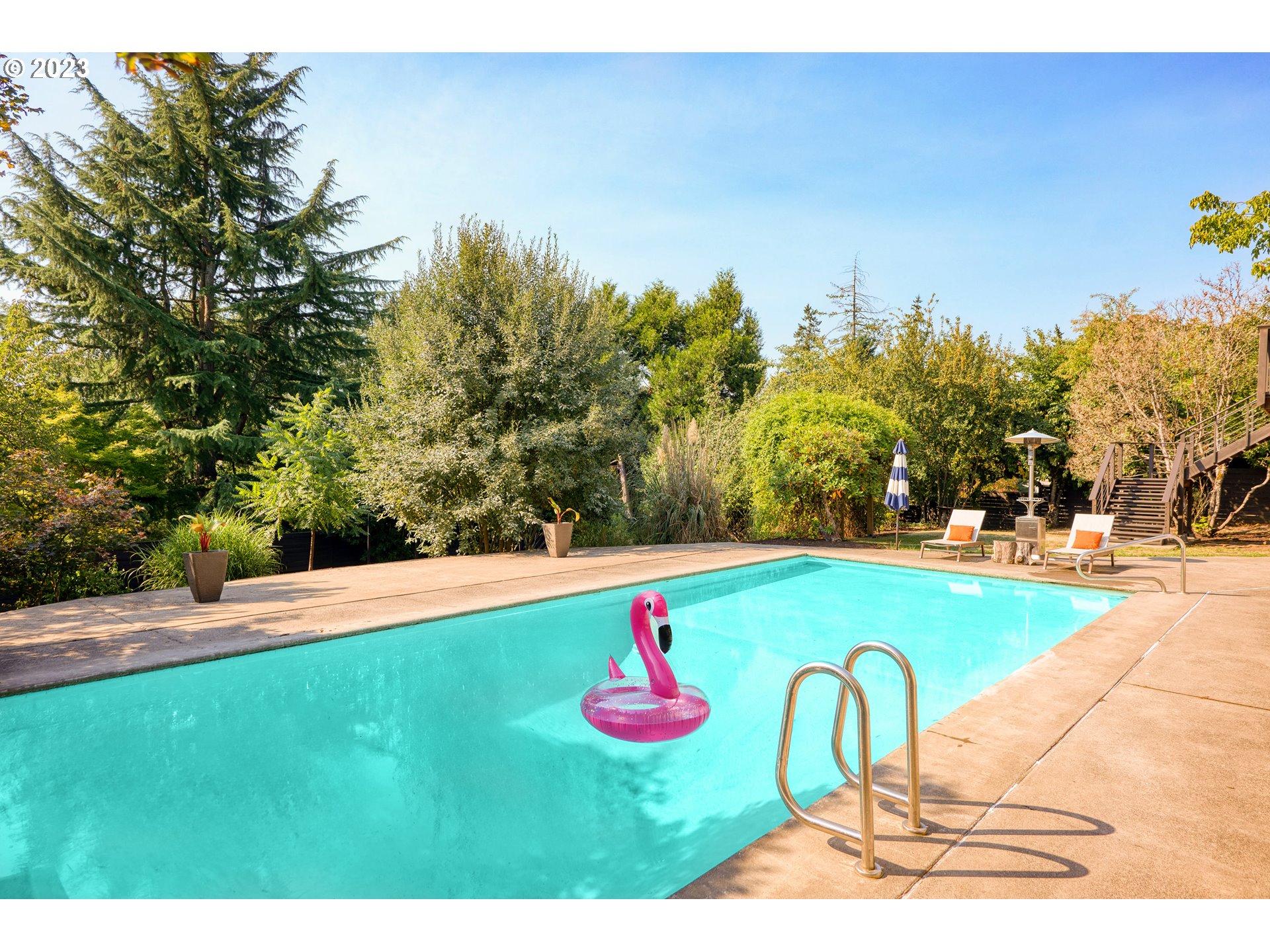 5914 Southwest Gunther Lane Portland, OR 97219 - Photo 34 of 40 a view of swimming pool outdoor seating and trees in the background