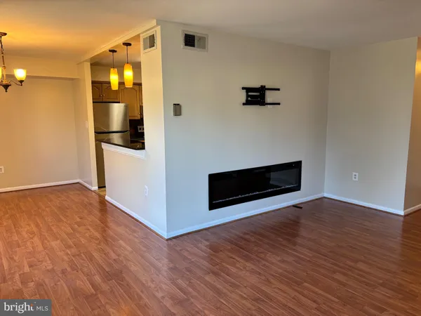 a view of an empty room with wooden floor and a ceiling fan