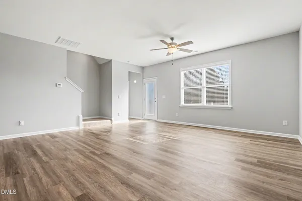a view of an empty room with a window and wooden floor