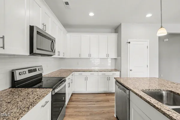 a kitchen with granite countertop a sink dishwasher stove and oven with wooden floor