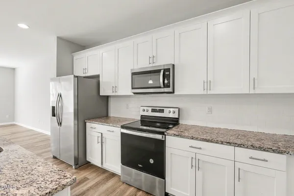 a kitchen with granite countertop white cabinets and stainless steel appliances