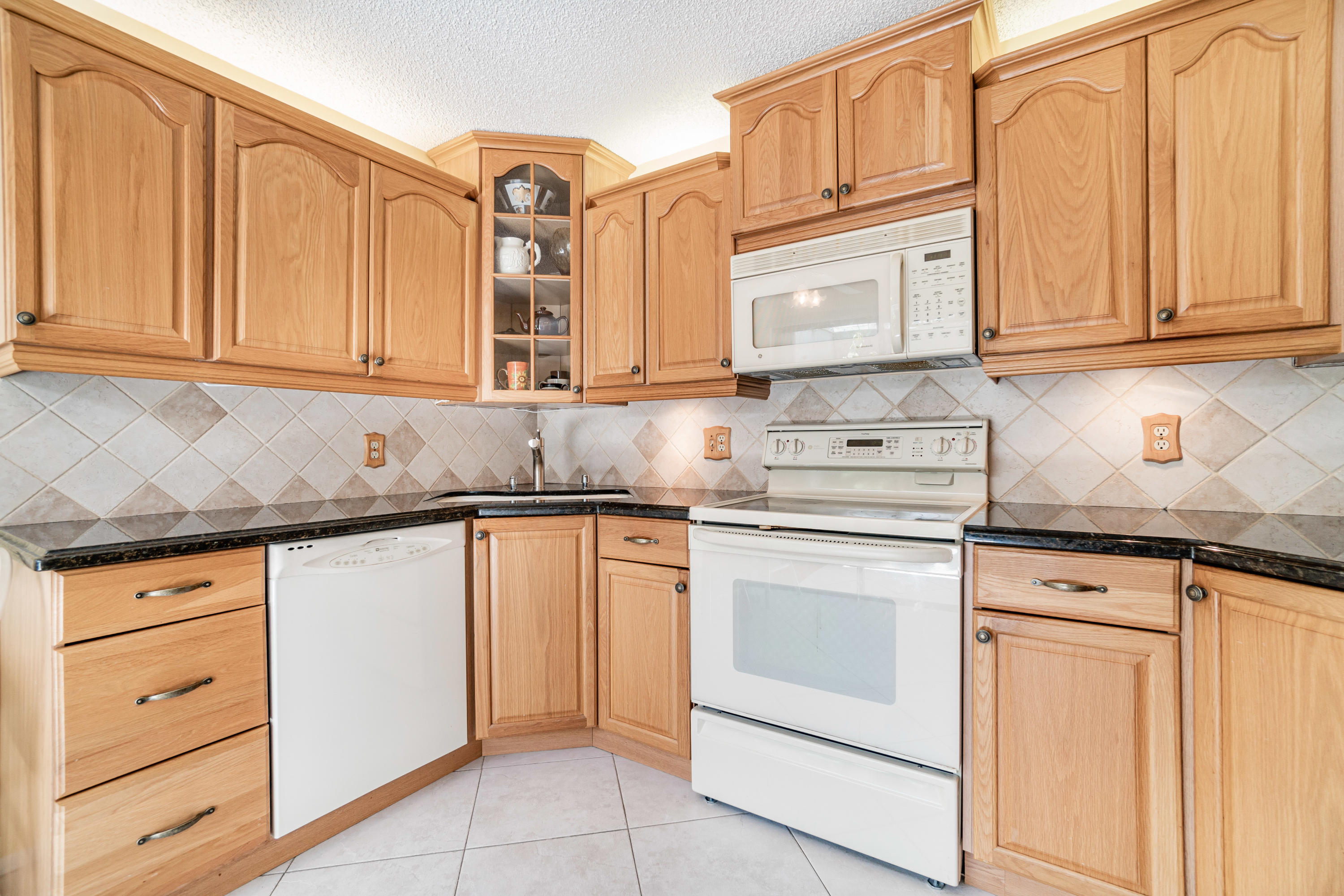 9159 Southwest 22nd Street, Unit D Boca Raton, FL 33428 - Photo 14 of 35 a kitchen with granite countertop white cabinets stainless steel appliances and sink
