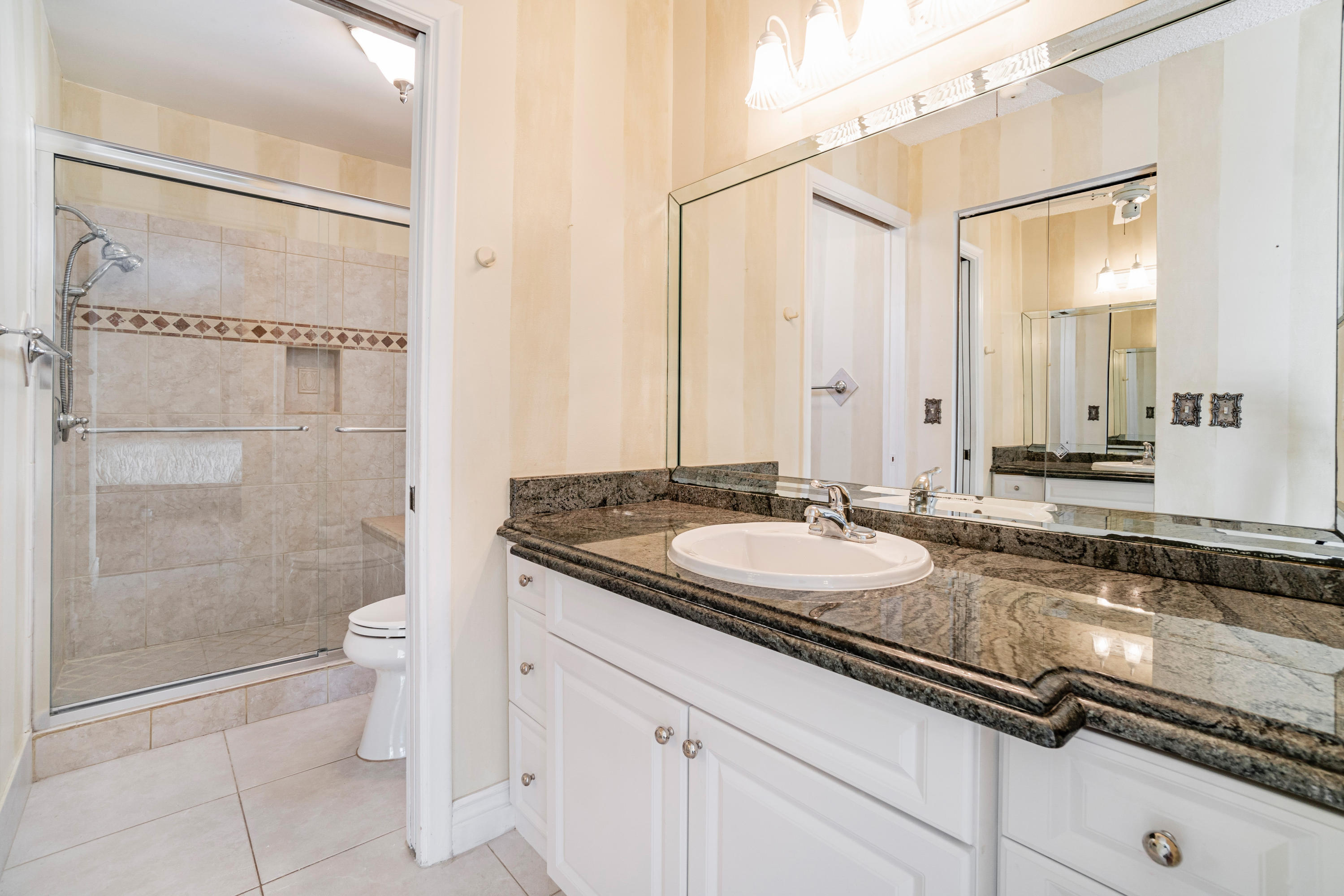 9159 Southwest 22nd Street, Unit D Boca Raton, FL 33428 - Photo 20 of 35 a bathroom with a granite countertop sink a toilet and shower
