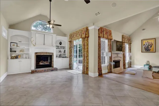 a view of a livingroom with a fireplace chandelier and windows