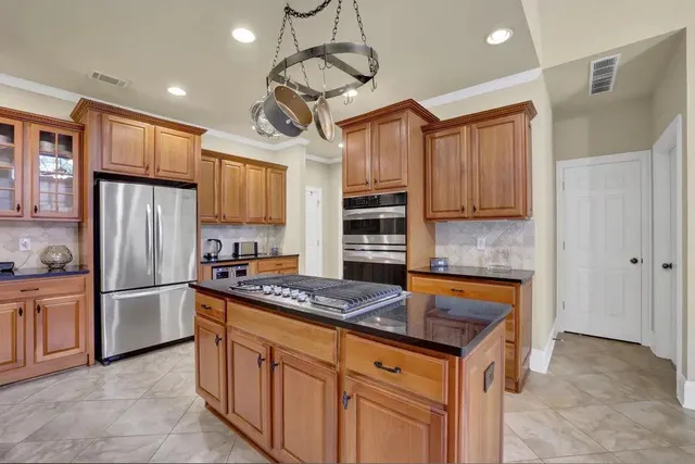 a kitchen with stainless steel appliances granite countertop a refrigerator a sink dishwasher a stove and a refrigerator with wooden cabinets