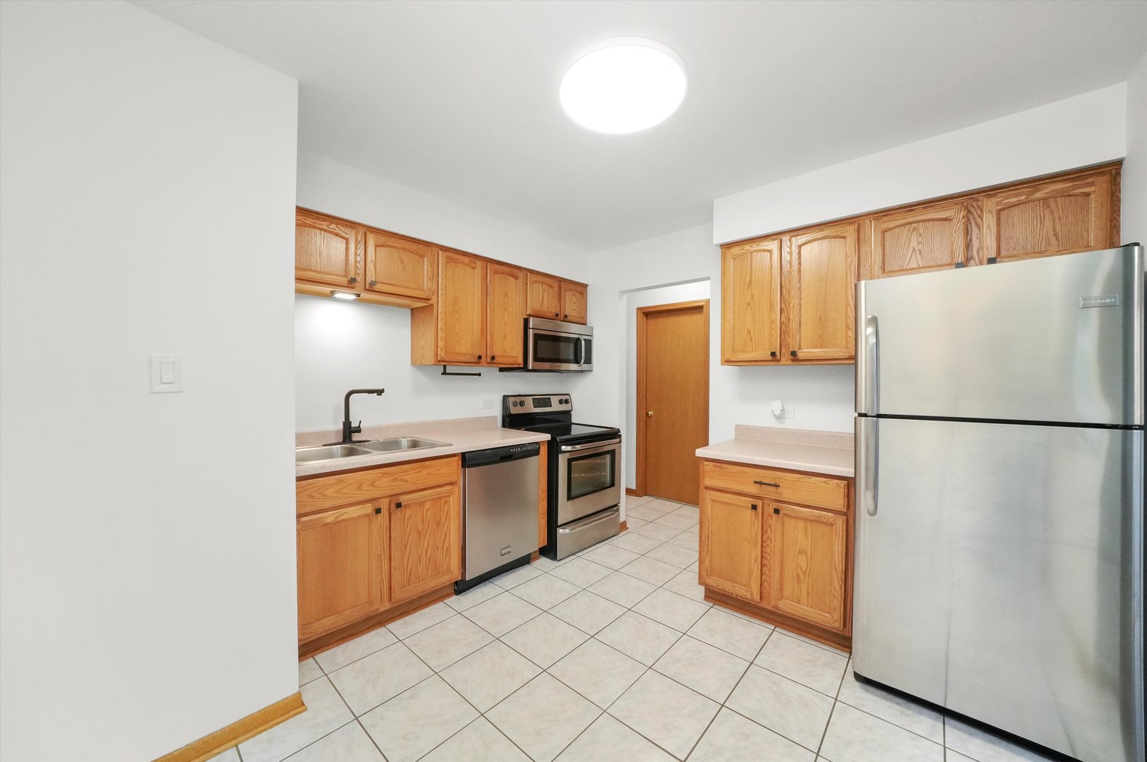 9016 West 140th Street, Unit 3A Orland Park, IL 60462 - Photo 10 of 25 a kitchen with a refrigerator sink and wooden cabinets