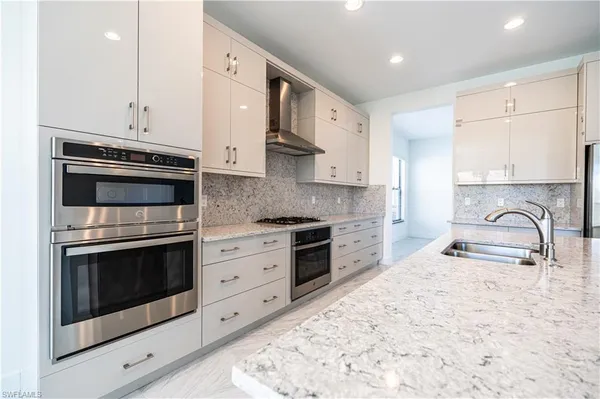 a kitchen with stainless steel appliances granite countertop a stove a sink and a microwave