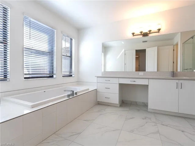 a spacious bathroom with a double vanity sink a mirror and a bathtub