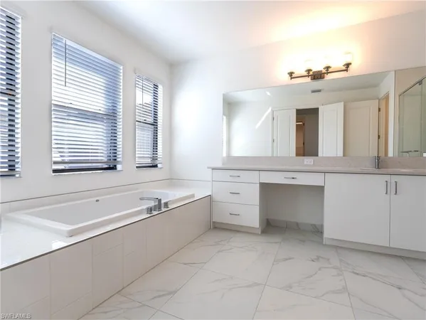 a spacious bathroom with a double vanity sink a mirror and a bathtub