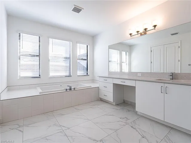a large white bathroom with a large tub sink and vanity