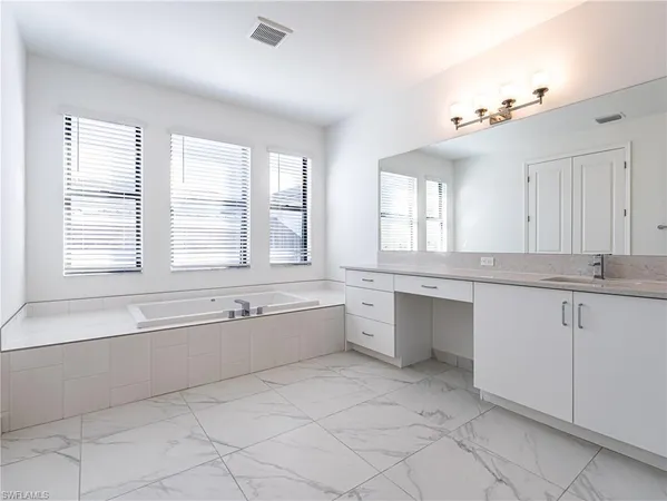 a large white bathroom with a large tub sink and vanity