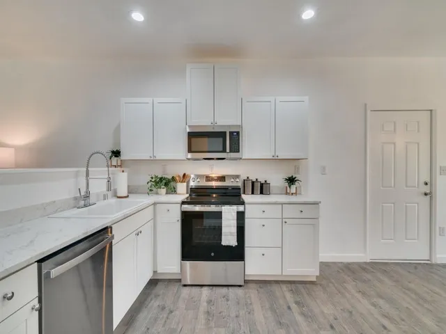 a kitchen with stainless steel appliances granite countertop a stove a sink and white cabinets