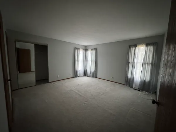 an empty room with windows and closet
