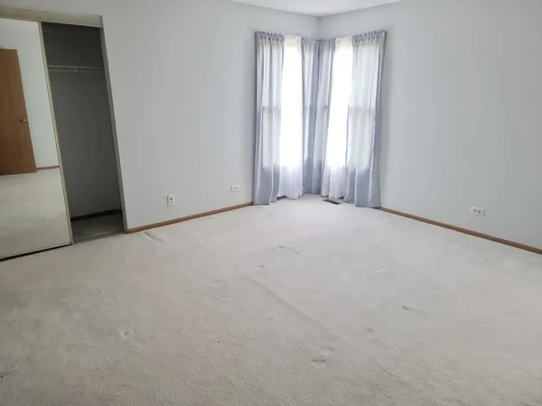 an empty room with windows and closet area