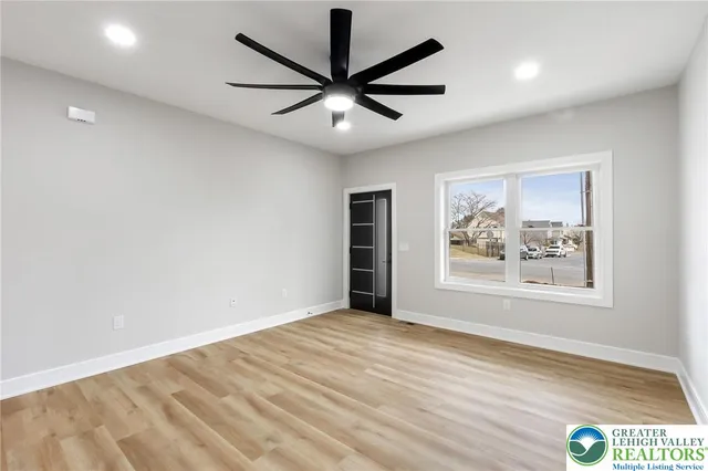 an empty room with wooden floor and windows