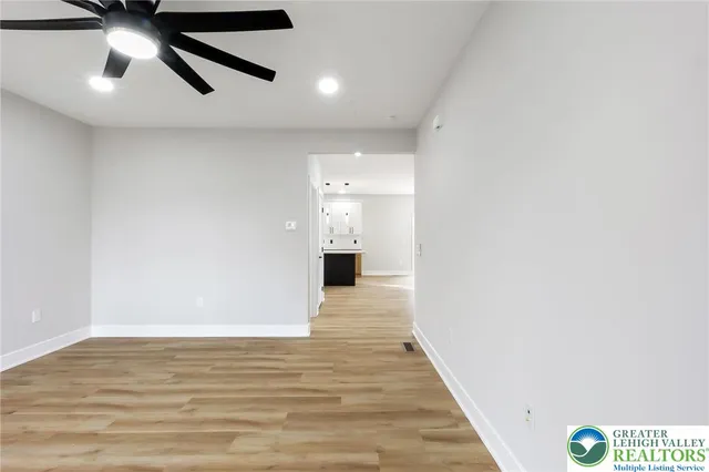 an empty room with wooden floor and ceiling fan