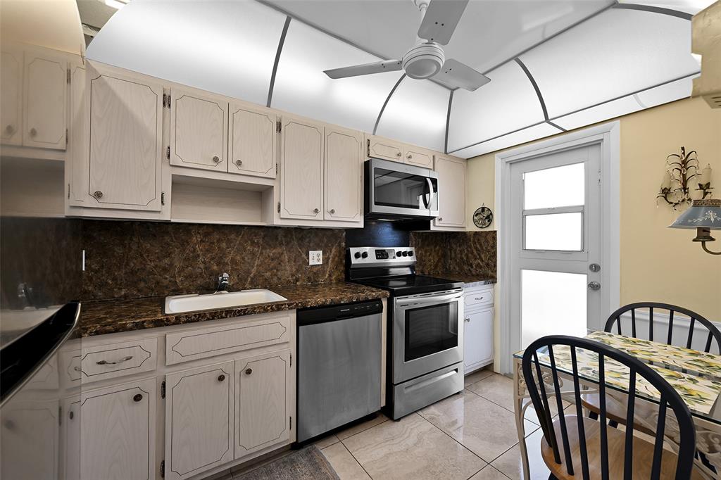 2350 Northeast 14th Street Causeway, Unit 609 Pompano Beach, FL 33062 - Photo 12 of 42 a kitchen with stainless steel appliances granite countertop a sink a stove white cabinets with a dining table and chairs