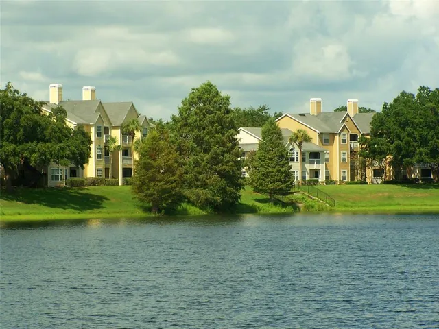 a view of a big house with a big yard and large trees