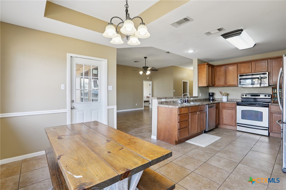 7114 Pappus Court Temple, TX 76502 - Photo 11 of 28 a kitchen with stainless steel appliances kitchen island granite countertop a stove a sink a refrigerator dining table and chairs