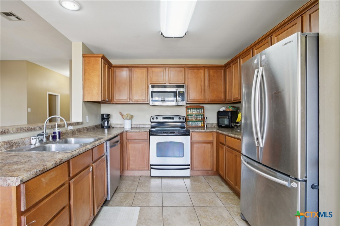 7114 Pappus Court Temple, TX 76502 - Photo 12 of 28 a kitchen with stainless steel appliances granite countertop a refrigerator sink and stove