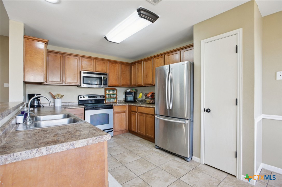 7114 Pappus Court Temple, TX 76502 - Photo 13 of 28 a kitchen with granite countertop a refrigerator a stove a sink a counter space and cabinets